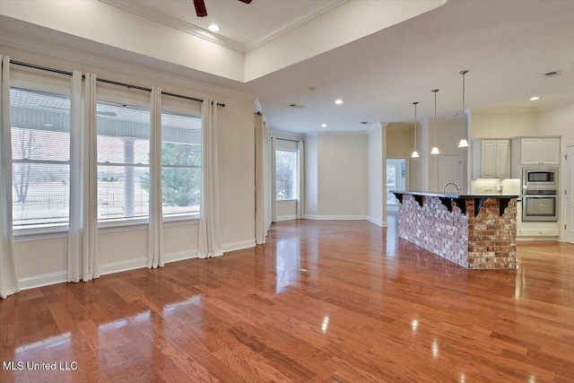 unfurnished living room with light hardwood / wood-style floors, ceiling fan, and ornamental molding