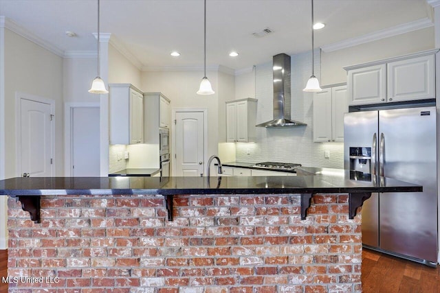 kitchen featuring decorative light fixtures, a kitchen breakfast bar, appliances with stainless steel finishes, and wall chimney exhaust hood