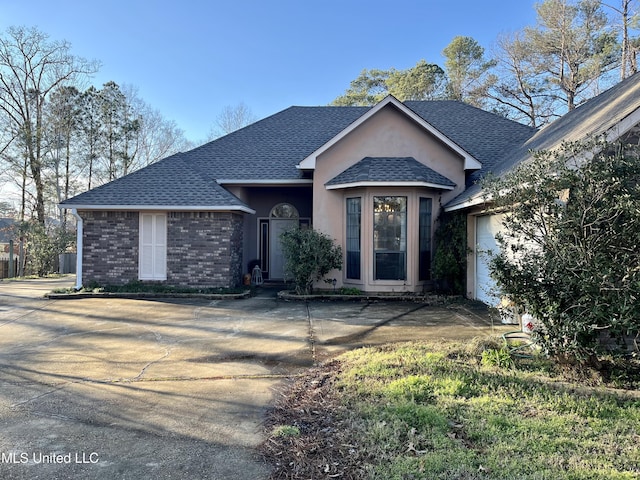 ranch-style home with brick siding, roof with shingles, and an attached garage