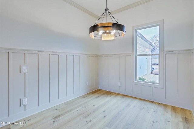 unfurnished dining area featuring crown molding, a healthy amount of sunlight, a chandelier, and light wood-type flooring