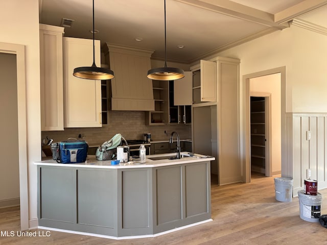 kitchen featuring tasteful backsplash, sink, decorative light fixtures, and light hardwood / wood-style floors