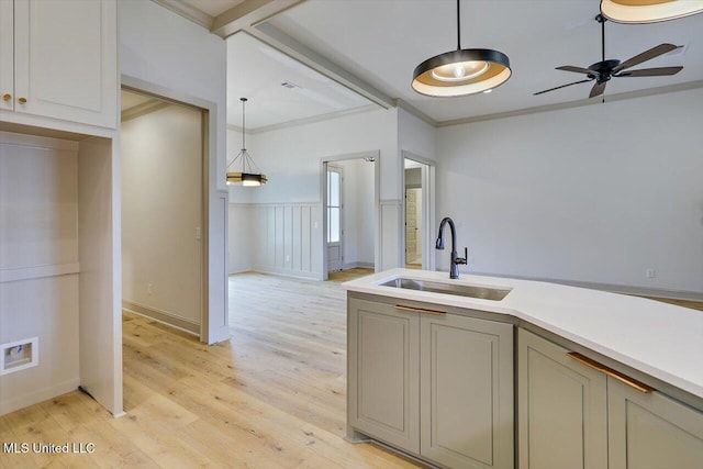 kitchen with sink, hanging light fixtures, light wood-type flooring, ornamental molding, and ceiling fan