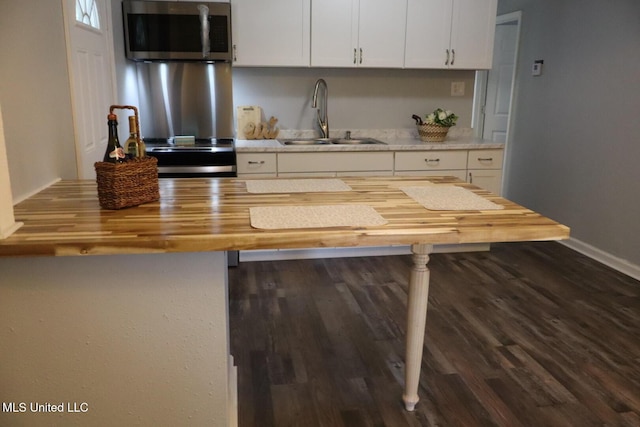 2411 14th St, Pascagoula, MS 39567 - kitchen with stainless steel microwave, butcher block countertops, a sink, dark wood-style floors, and white cabinets