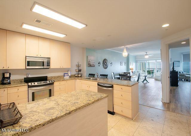 kitchen featuring light stone counters, appliances with stainless steel finishes, light hardwood / wood-style flooring, and kitchen peninsula