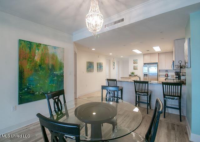 dining room with ornamental molding, a notable chandelier, and light wood-type flooring