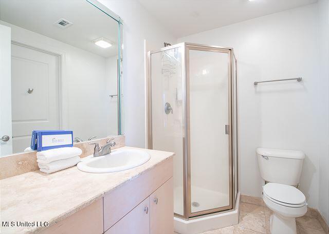 bathroom with a shower with door, toilet, tile patterned floors, and vanity