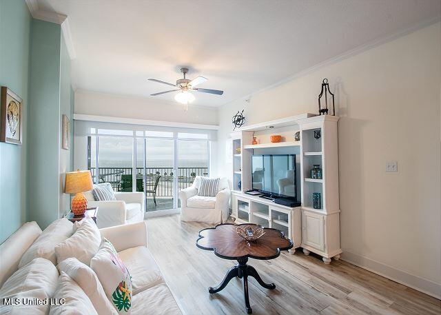 living room with ceiling fan, ornamental molding, and light wood-type flooring