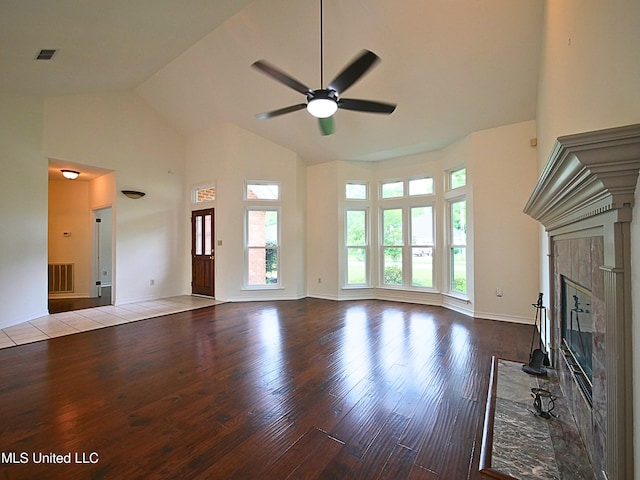 7869 Hilo Way, Diamondhead, MS 39525 - unfurnished living room with high vaulted ceiling, wood finished floors, a tiled fireplace, a ceiling fan, and baseboards