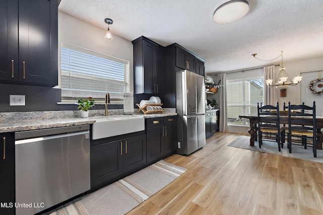 kitchen with decorative light fixtures, a textured ceiling, stainless steel appliances, and sink