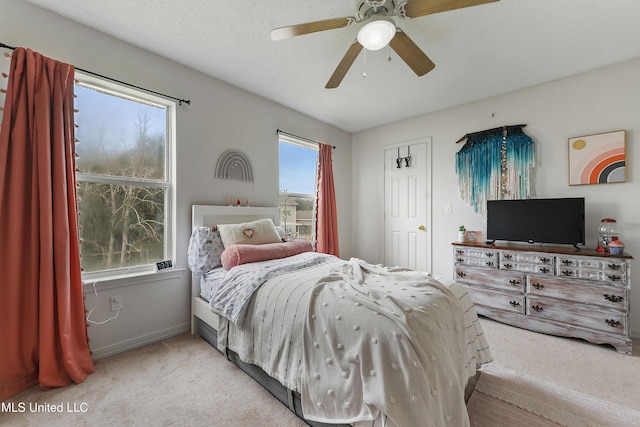 bedroom with ceiling fan, light colored carpet, and a textured ceiling