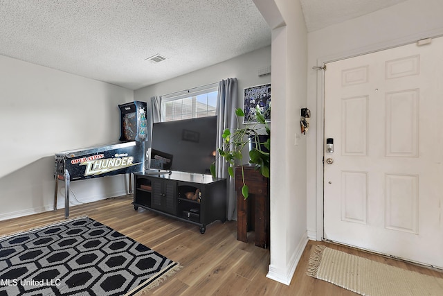 foyer entrance with hardwood / wood-style floors and a textured ceiling