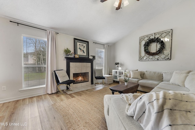 living room featuring a wealth of natural light, a fireplace, vaulted ceiling, and light hardwood / wood-style flooring