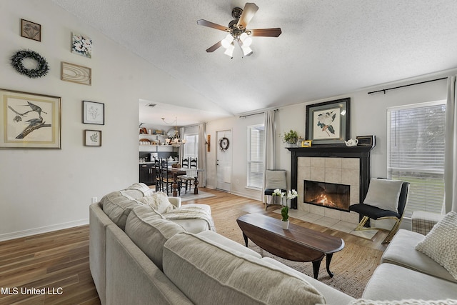 living room with a fireplace, hardwood / wood-style floors, a textured ceiling, and vaulted ceiling