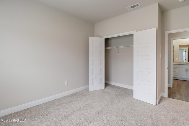 unfurnished bedroom featuring light colored carpet and a closet