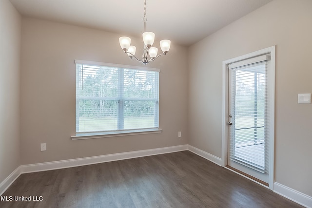 unfurnished dining area with a wealth of natural light, an inviting chandelier, and dark hardwood / wood-style floors