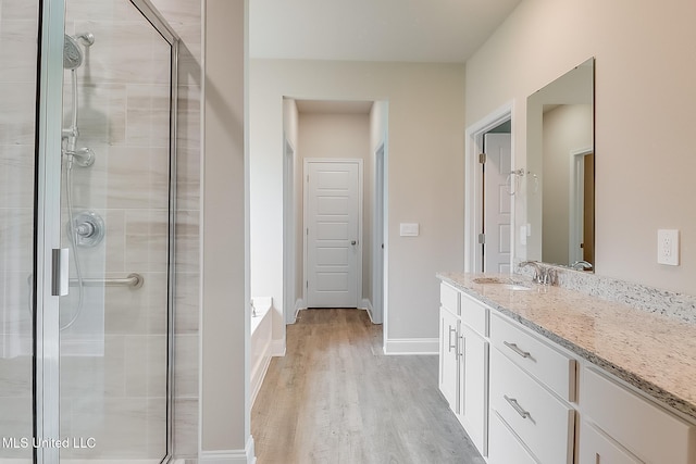 bathroom with hardwood / wood-style flooring, vanity, and shower with separate bathtub