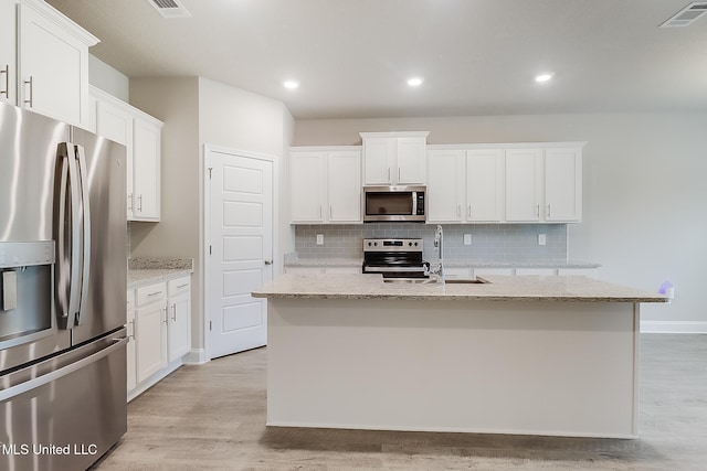 kitchen with an island with sink, white cabinetry, light hardwood / wood-style flooring, and appliances with stainless steel finishes