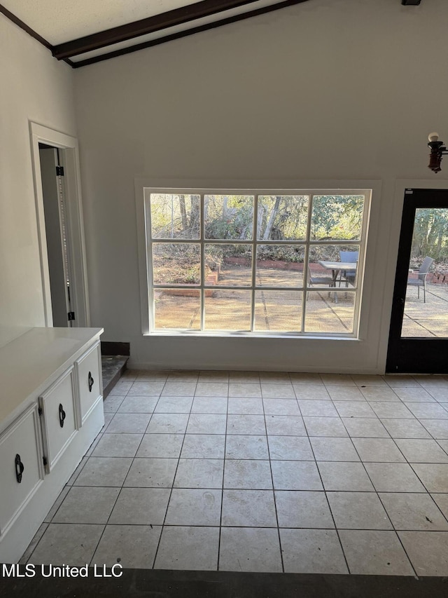 interior space featuring light tile patterned flooring and beamed ceiling