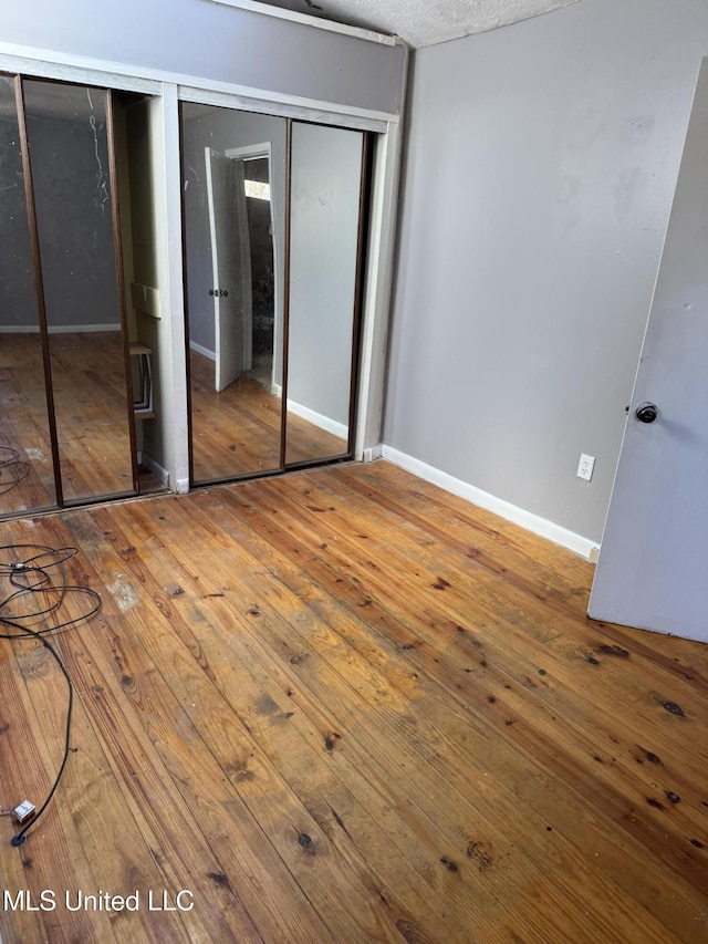 unfurnished bedroom with a closet and wood-type flooring