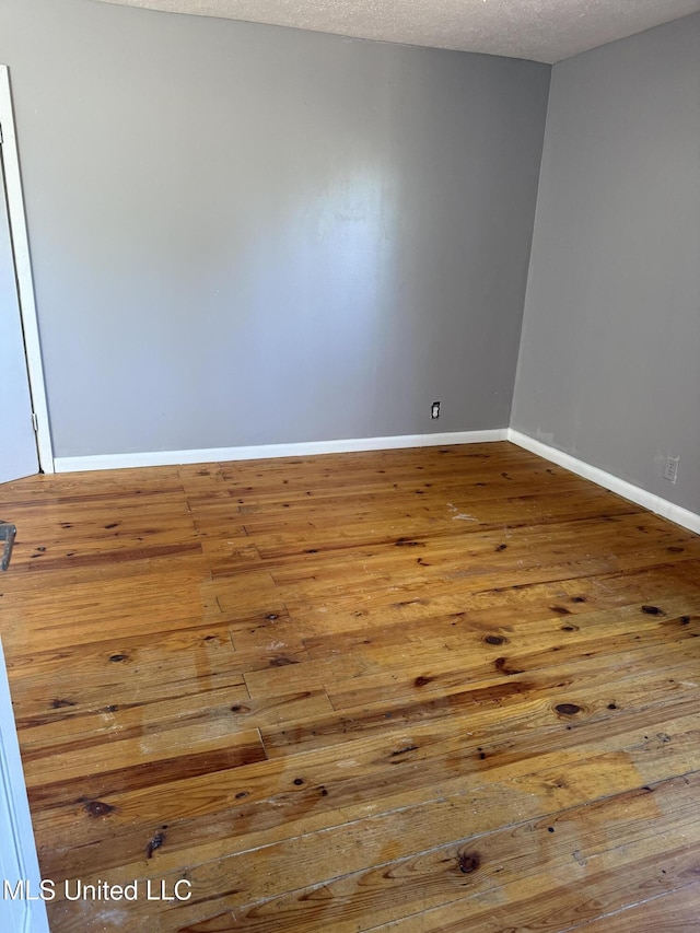 unfurnished room with wood-type flooring and a textured ceiling