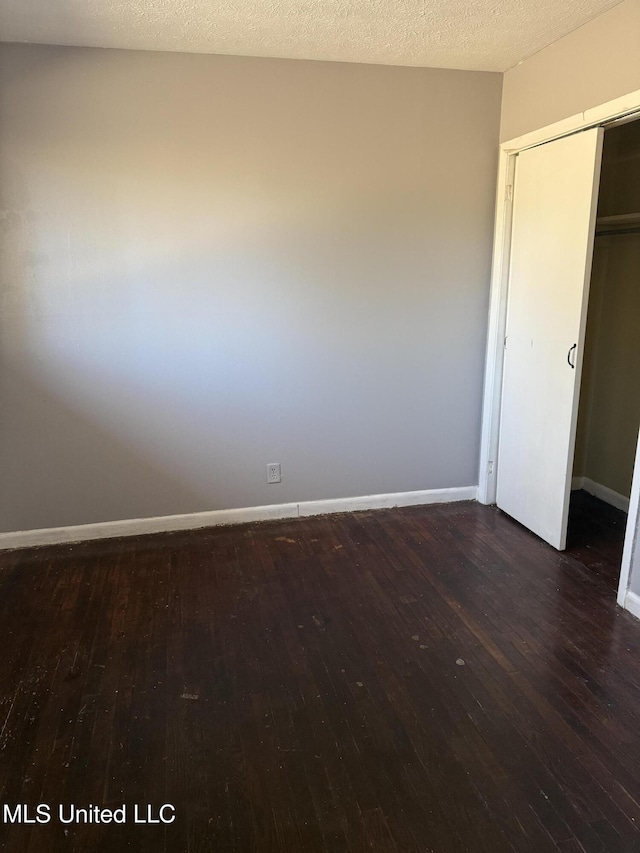 unfurnished bedroom featuring a closet, dark hardwood / wood-style floors, and a textured ceiling