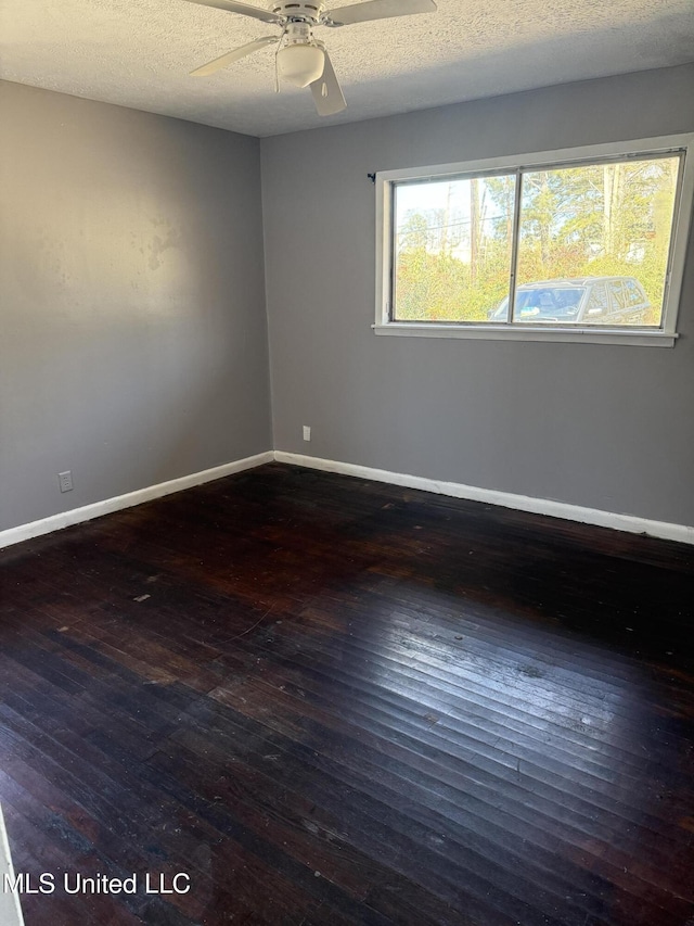 empty room with a textured ceiling, ceiling fan, and dark hardwood / wood-style flooring