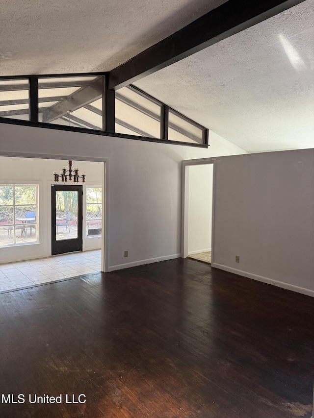 unfurnished living room featuring a textured ceiling, wood-type flooring, and vaulted ceiling with beams