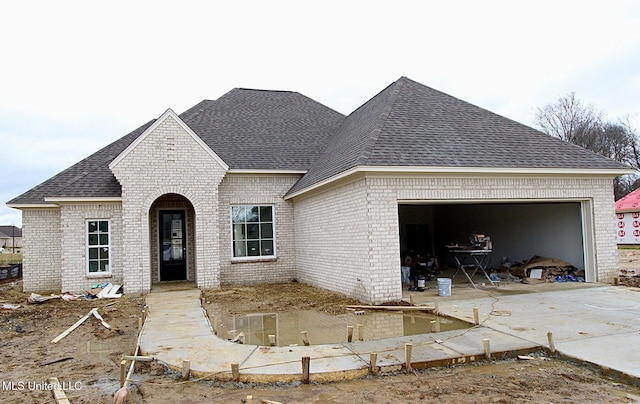 view of front facade featuring a garage, driveway, brick siding, and roof with shingles