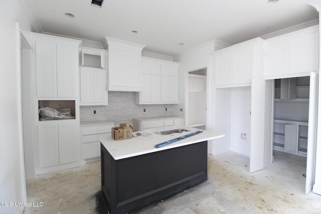 kitchen with white cabinets, a kitchen island, decorative backsplash, and unfinished concrete floors