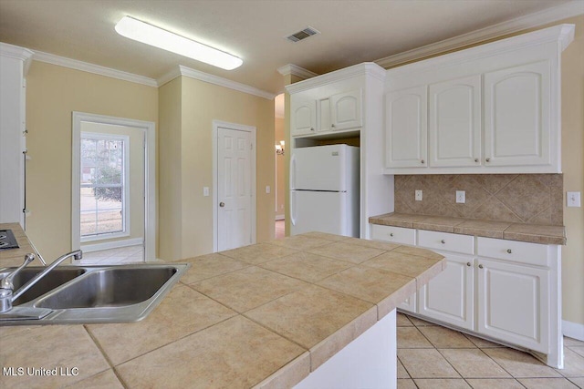 kitchen featuring sink, white cabinetry, white refrigerator, tile counters, and ornamental molding