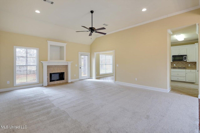 unfurnished living room with vaulted ceiling, ornamental molding, light colored carpet, and ceiling fan