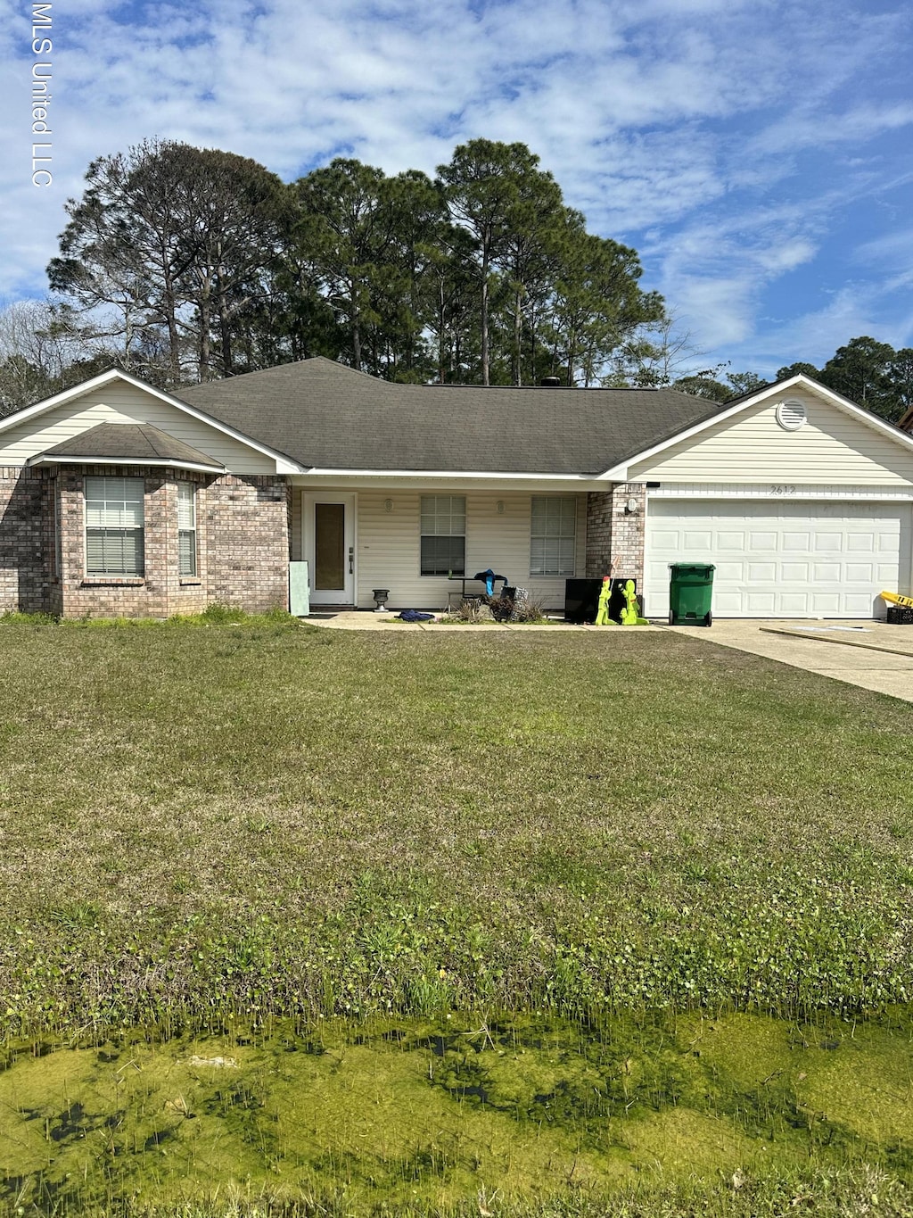 ranch-style house with a front yard, concrete driveway, brick siding, and an attached garage