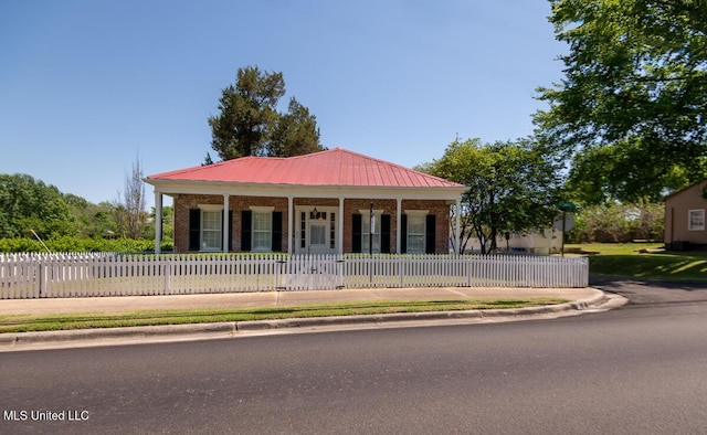 view of front of home with a fenced front yard, a porch, metal roof, and brick siding