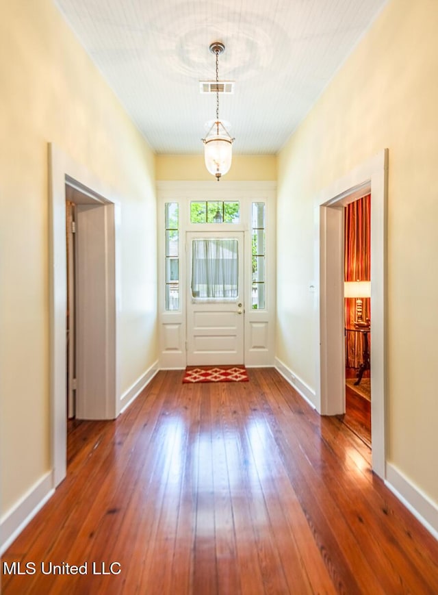 doorway with baseboards, visible vents, and hardwood / wood-style floors