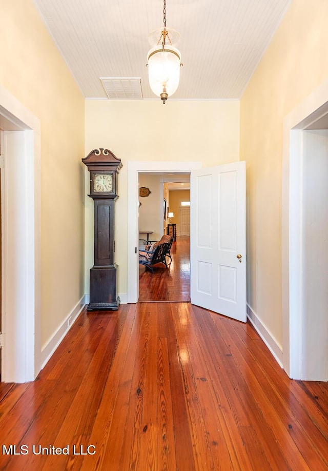 corridor featuring visible vents, baseboards, and hardwood / wood-style flooring