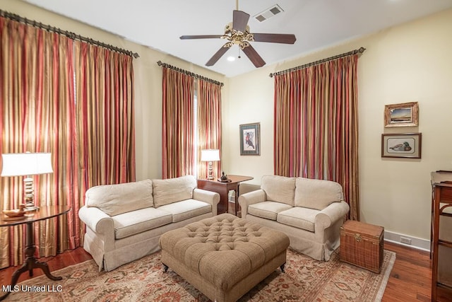 living area featuring baseboards, ceiling fan, wood finished floors, and visible vents
