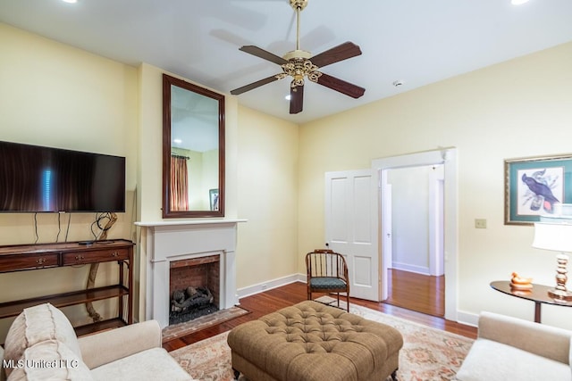 living room featuring ceiling fan, recessed lighting, baseboards, a fireplace with flush hearth, and wood finished floors