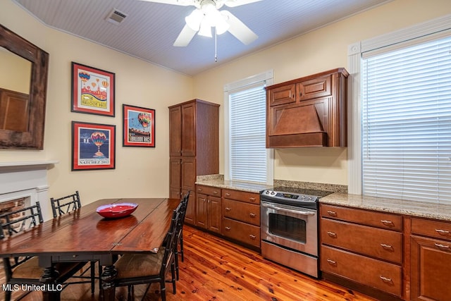 kitchen featuring ceiling fan, electric range, visible vents, light stone counters, and hardwood / wood-style floors