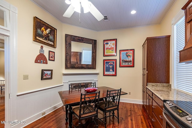 dining area featuring crown molding, a wainscoted wall, ceiling fan, and dark wood-style floors