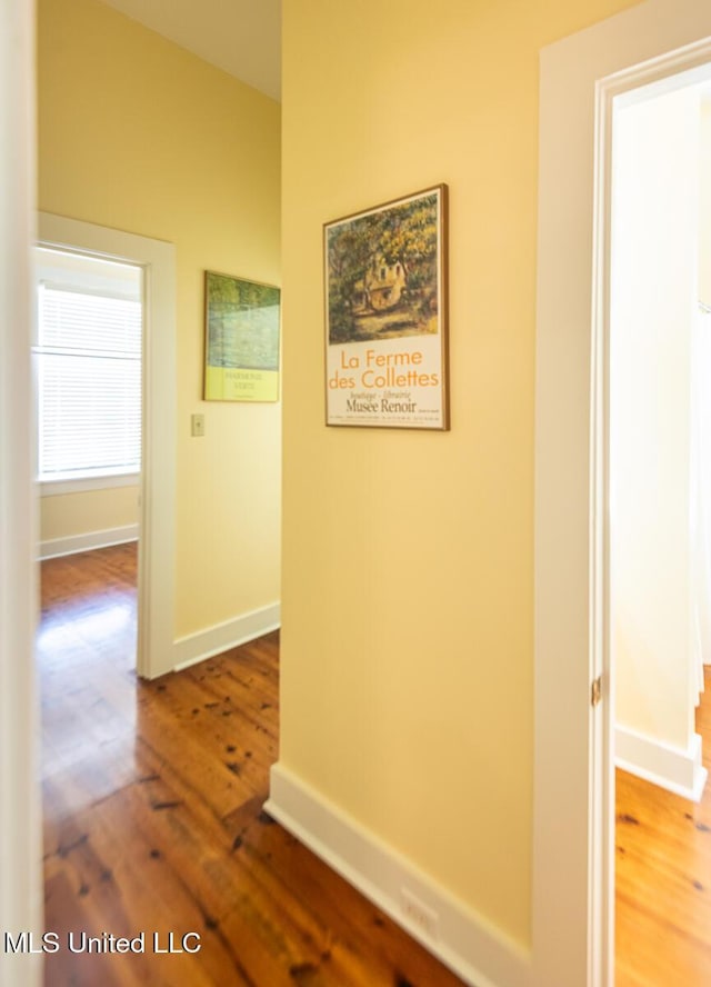 corridor featuring baseboards and wood finished floors