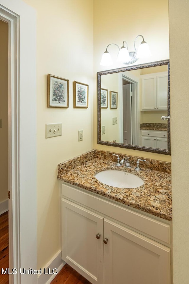 bathroom featuring vanity, baseboards, and wood finished floors