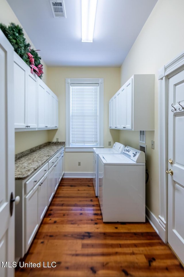 clothes washing area with cabinet space, washing machine and dryer, baseboards, visible vents, and dark wood-style floors