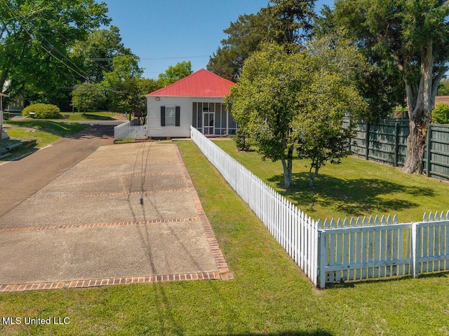 rear view of house with a yard, metal roof, and fence private yard
