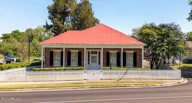 view of front of property with covered porch, brick siding, a fenced front yard, and metal roof