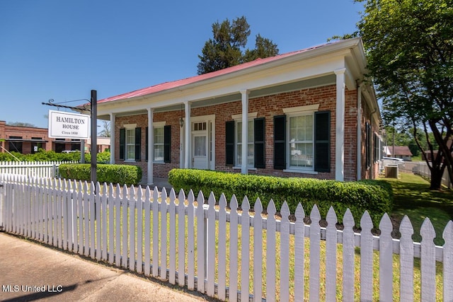 view of front of home featuring covered porch, brick siding, and a fenced front yard