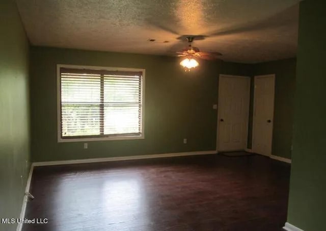 empty room with dark hardwood / wood-style floors, a textured ceiling, and ceiling fan