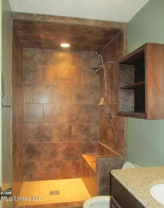 bathroom with vanity, tiled shower, and toilet