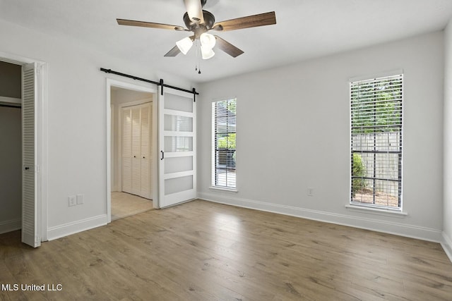132 Bent Creek Dr, Brandon, MS 39047 - unfurnished bedroom with a barn door, wood finished floors, and two closets