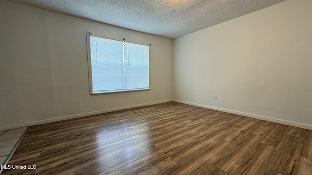 empty room with a textured ceiling and dark hardwood / wood-style flooring