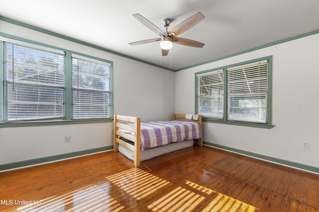 unfurnished bedroom with ceiling fan, crown molding, and wood-type flooring